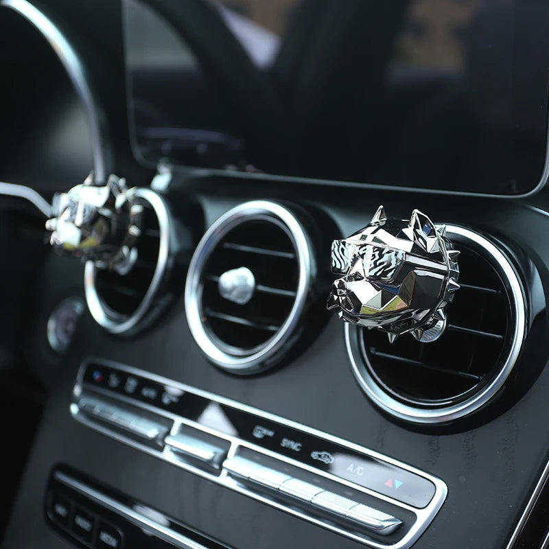 Close-up of silver bulldog car vent diffuser on black dashboard.