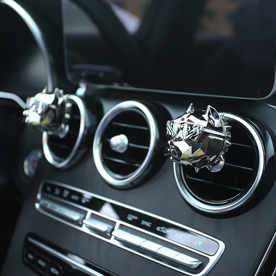 Close-up of silver bulldog car vent diffuser on black dashboard.