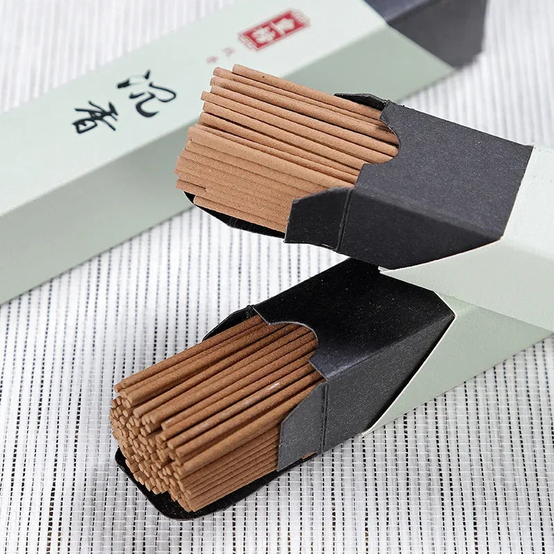 Close-up of sandalwood incense sticks emerging from textured gray packaging