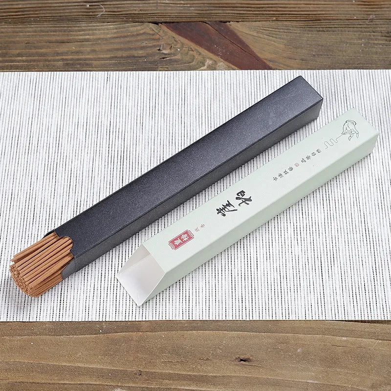 Flat lay of single sandalwood incense box with partially revealed incense sticks on wood surface