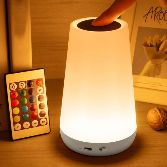 Remote-controlled LED bedside lamp glowing white on a wooden surface.